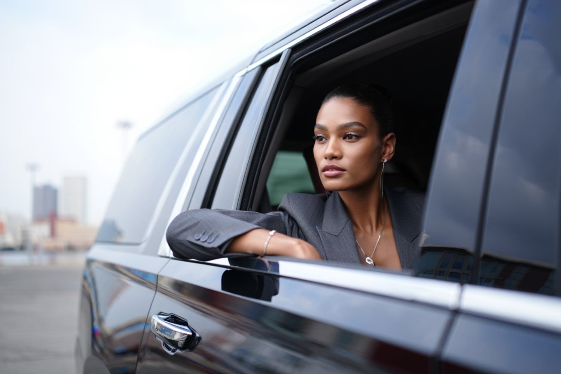 Guest with her arm on the open window of a chauffeured SUV